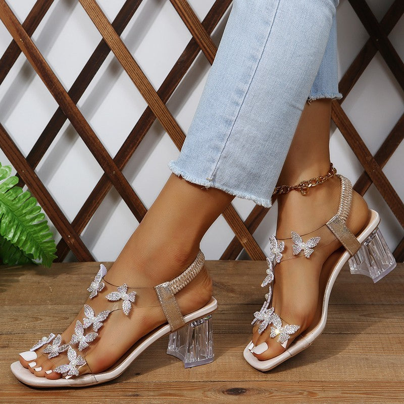 Sandales Glamour pour dames avec des détails de papillon scintillants et un talon bloc transparent Chic und Stil