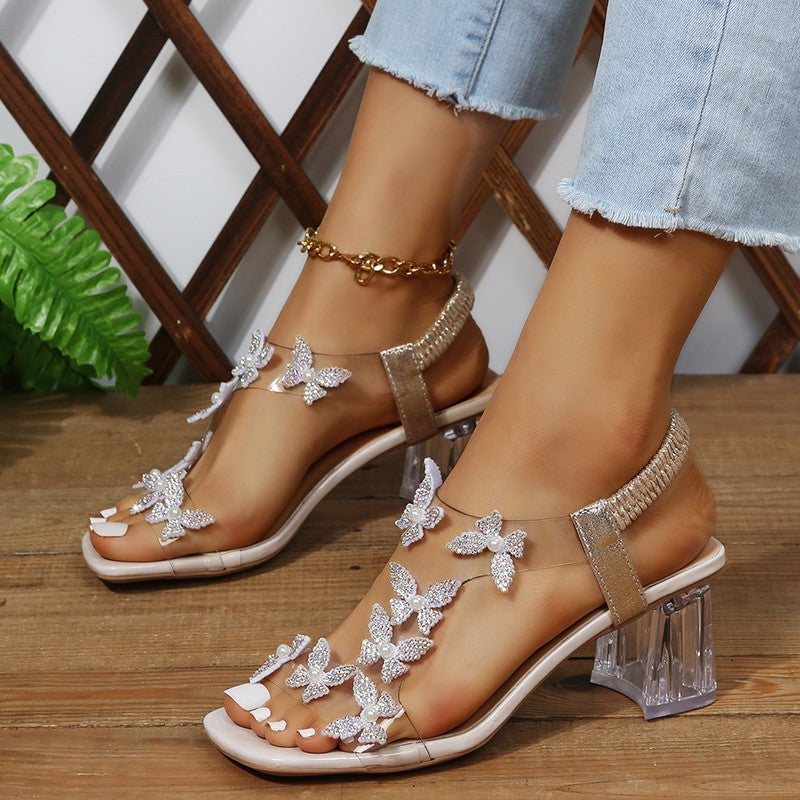 Sandales Glamour pour dames avec des détails de papillon scintillants et un talon bloc transparent Chic und Stil