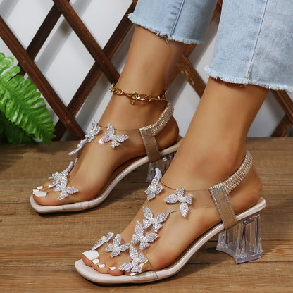Sandales Glamour pour dames avec des détails de papillon scintillants et un talon bloc transparent Chic und Stil