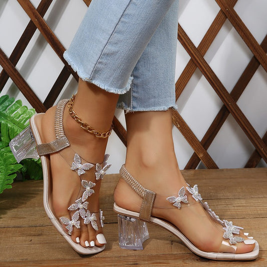 Sandales Glamour pour dames avec des détails de papillon scintillants et un talon bloc transparent Chic und Stil