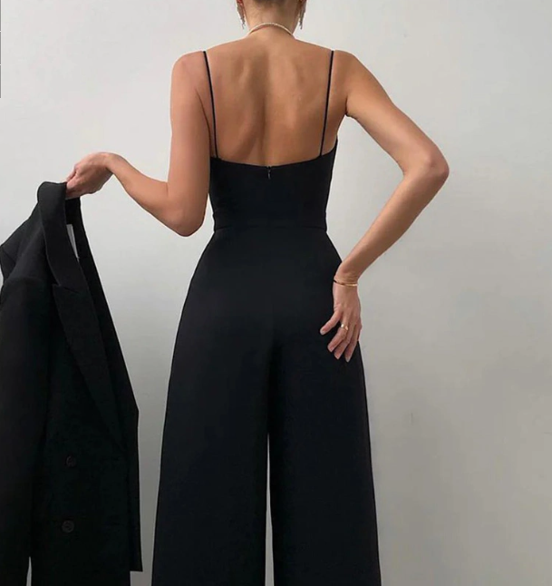 Rückenansicht eines model in einem schwarz sexy riemen-overall, das einen blazer hält