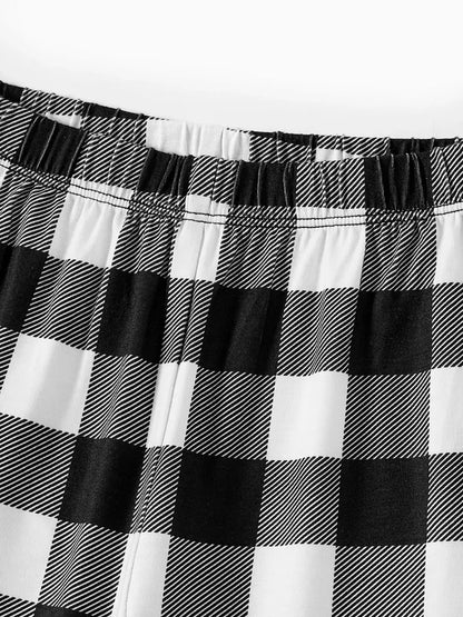 Chic und Stil | "2025 FAMILY CHRISTMAS" text and sled pattern - Black long sleeve top with black and white checkered pants family matching pajamas